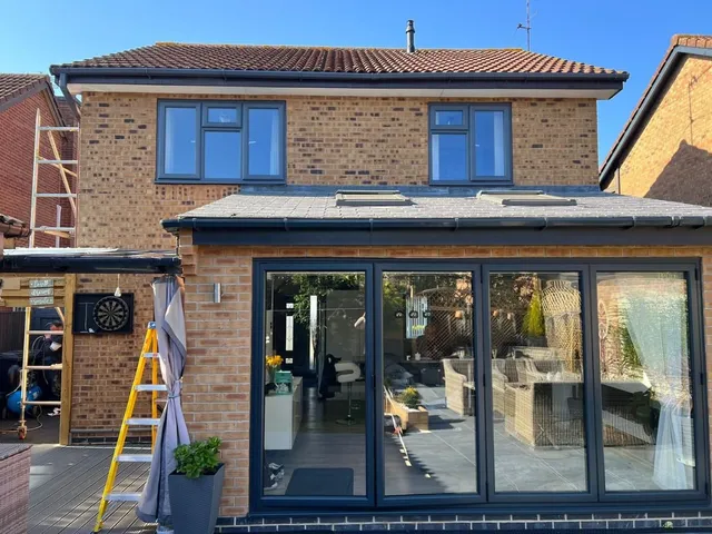 Modern brick house extension featuring spray coated grey window frames and bi-fold doors by Inspire Spray Coat.